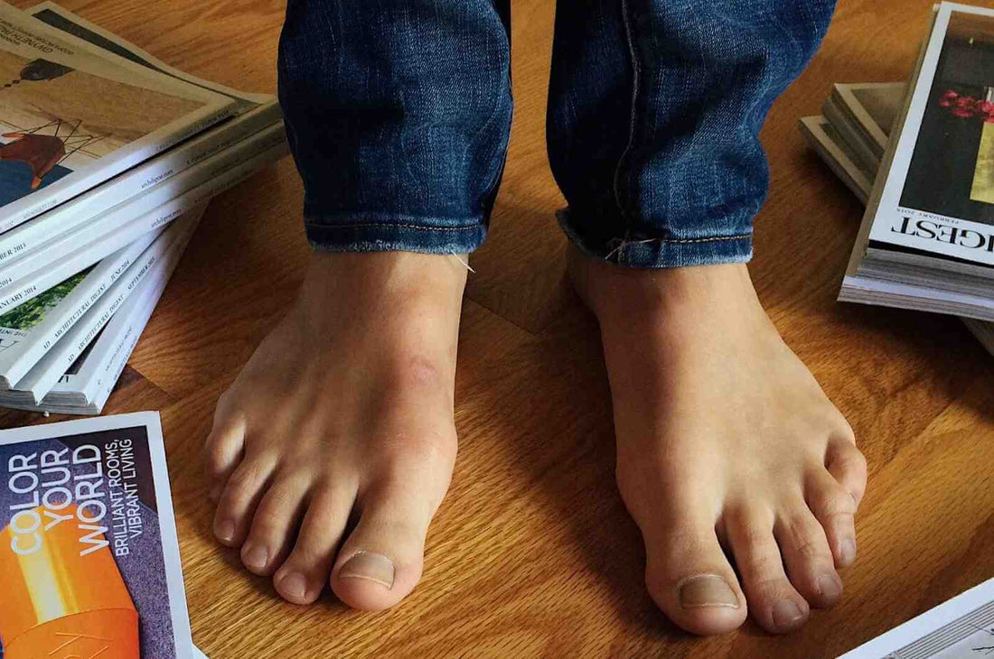 Homme en jean pieds nus sur le parquet de chêne jonché de magazine recherche ses chaussettes grande taille pour aller travailler