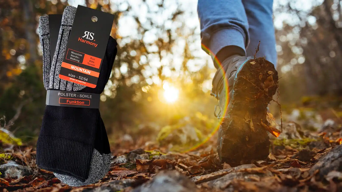Un homme en chaussures de randonnée marche en forêt dans les feuilles mortes avec des chaussettes de rando grandes tailles aux pieds.