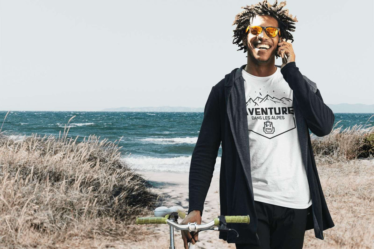 Jeune homme à vélo se promène le long de la plage avec son vélo et ses chaussettes grande taille dans ses sneakers